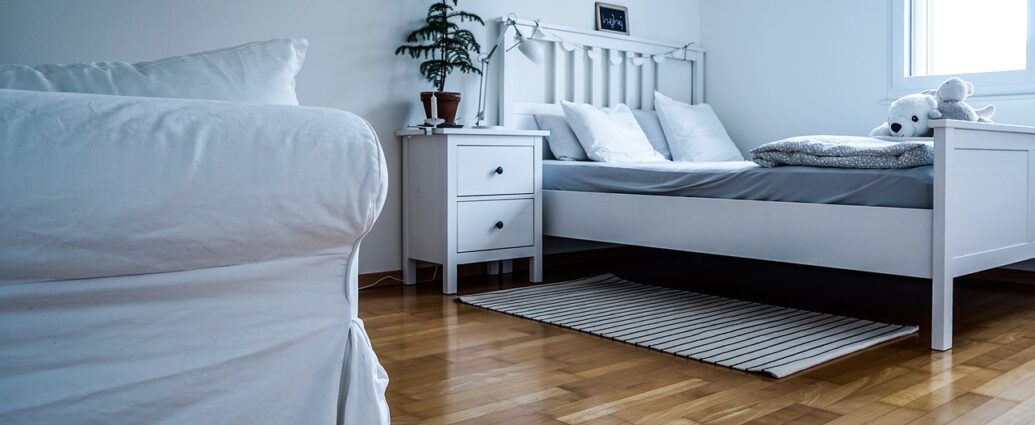 Biała sypialnia z drewnianą podłogą