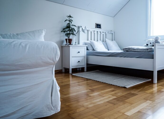 Biała sypialnia z drewnianą podłogą