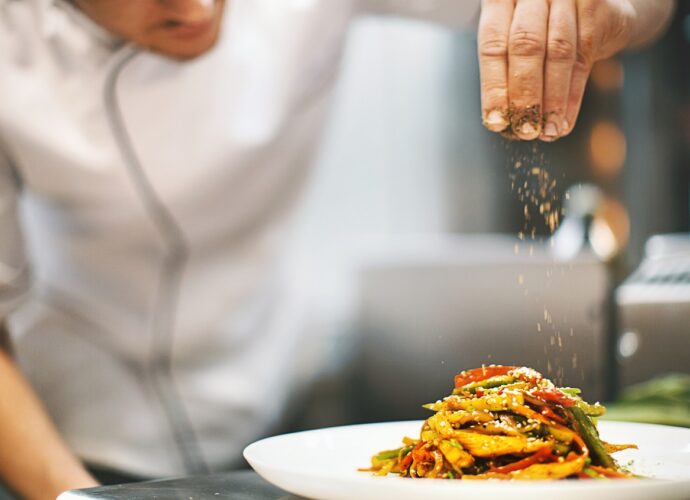 Kucharz doprawia danie pikantnymi przyprawami