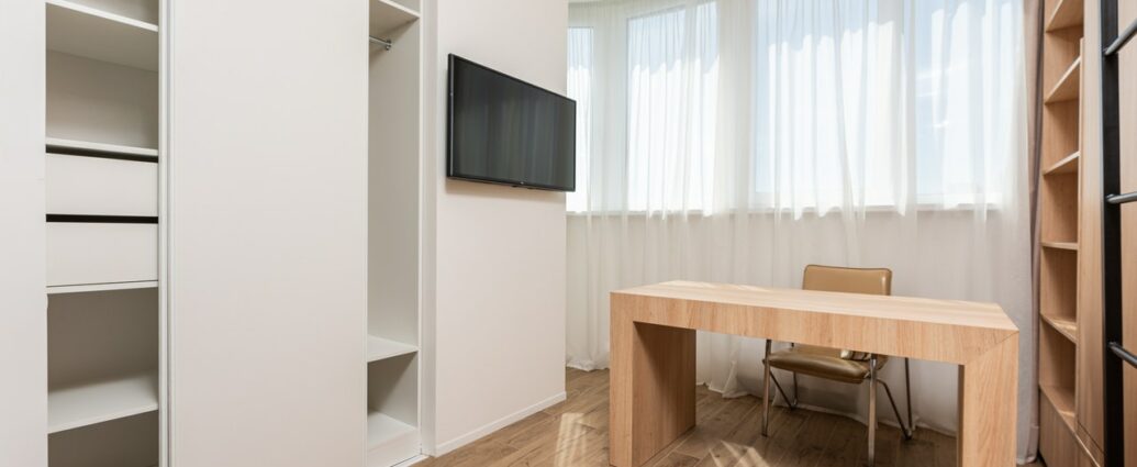 Biurko z naturalnego drewna w nowoczesnym pokoju z białymi meblami