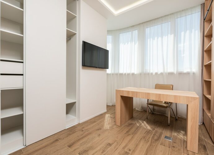 Biurko z naturalnego drewna w nowoczesnym pokoju z białymi meblami