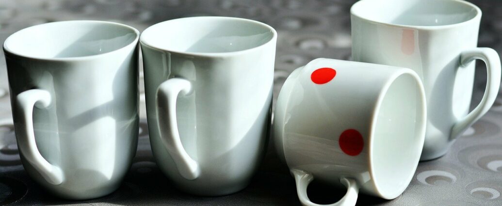Białe kubki porcelanowe na kamiennym blacie