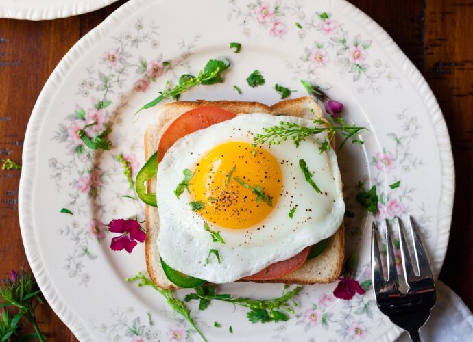 Idealnie usmażone jajko sadzone posypane ziołami na gorącym toście