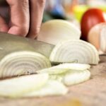 Kucharz kroi cebulę w półkrążki nożem szefa