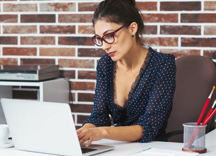 Kobieta w okularach pracuje przy laptopie