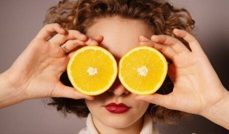 Kobieta trzyma w dłoniach plasterki pomarańczy