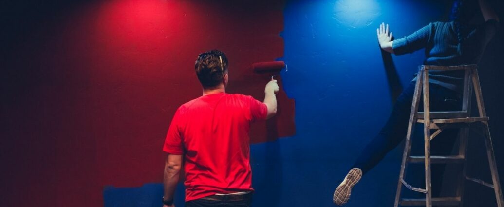 Dwie osoby malują ścianę na czerwono i niebiesko