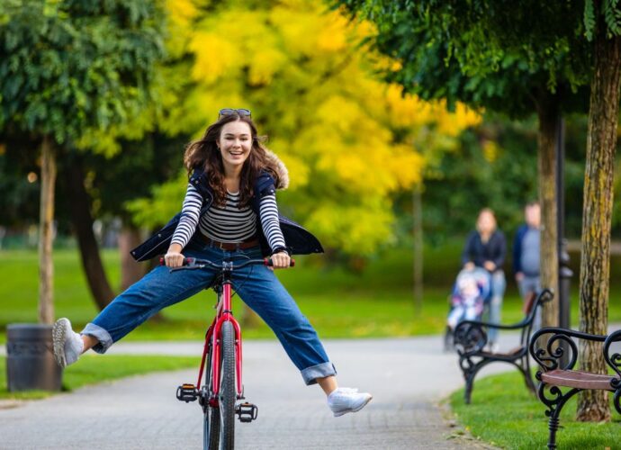 Dziewczyna jedzie na rowerze alejką w parku
