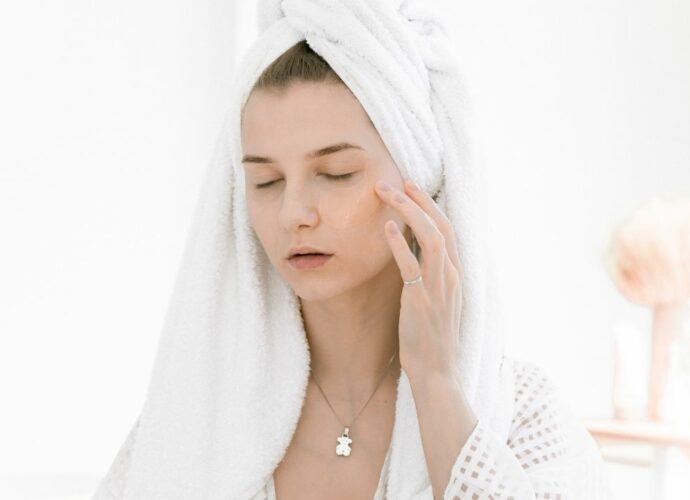 Kobieta pielęgnuje skórę twarzy i włosy emolientami