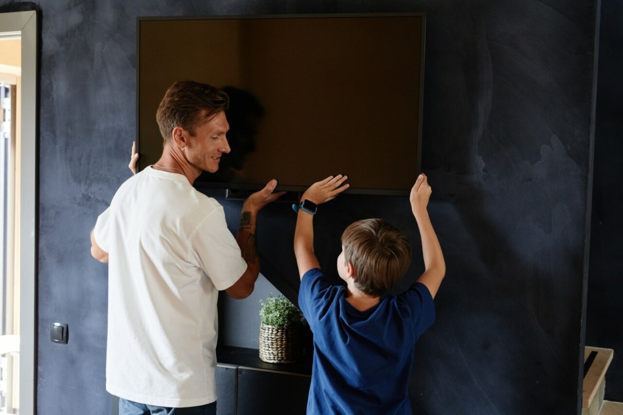 Ojciec z synem wieszają telewizor na ścianie