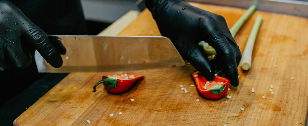 Krojenie świeżej papryczki chili - kucharz kroi papryczkę w rękawiczkach