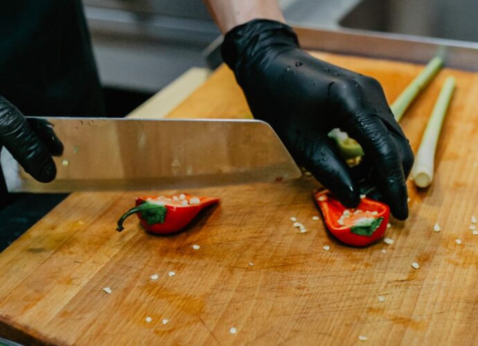 Krojenie świeżej papryczki chili - kucharz kroi papryczkę w rękawiczkach