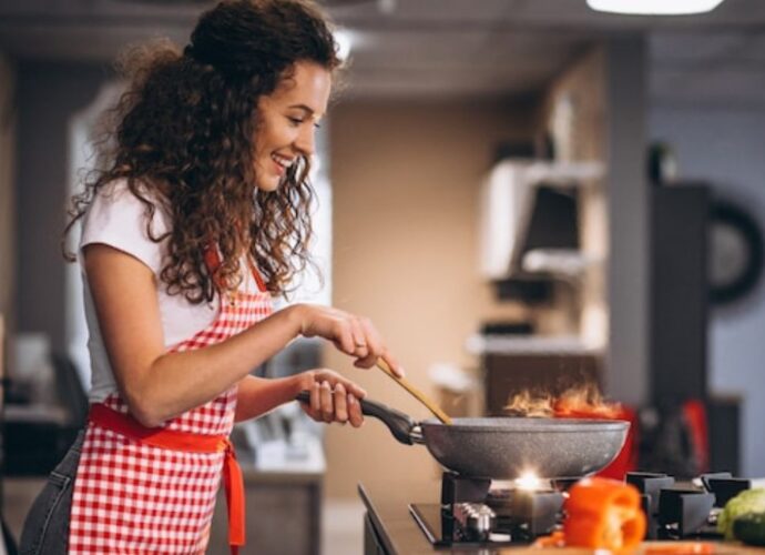 Kobieta przygotowuje danie na patelni. Jaką patelnię wybrać - aluminiową czy granitową?