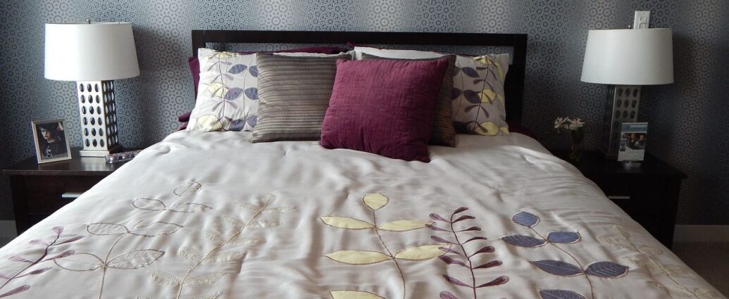 Pościelone łóżko, przykryte narzutą, z ułożonymi poduszkami