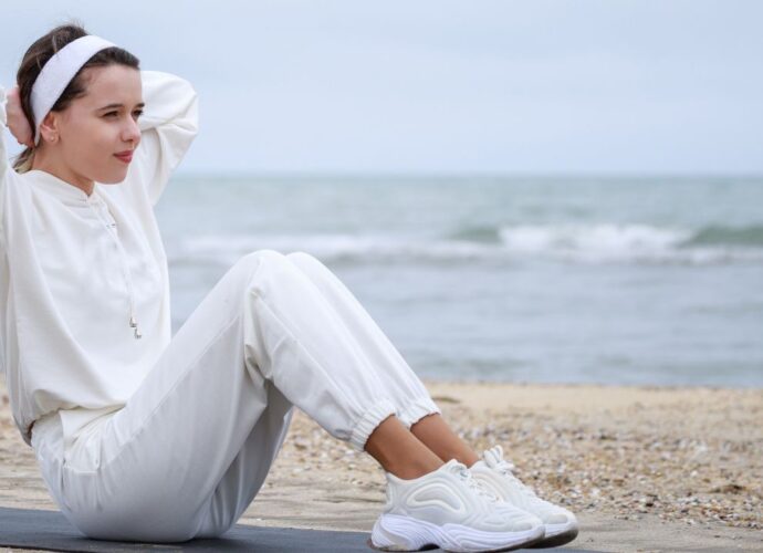 Młoda kobieta na plaży w białym komplecie dresowym