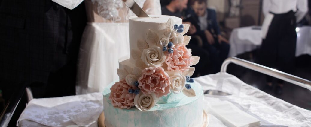 Młoda para kroi tort weselny udekorowany różami