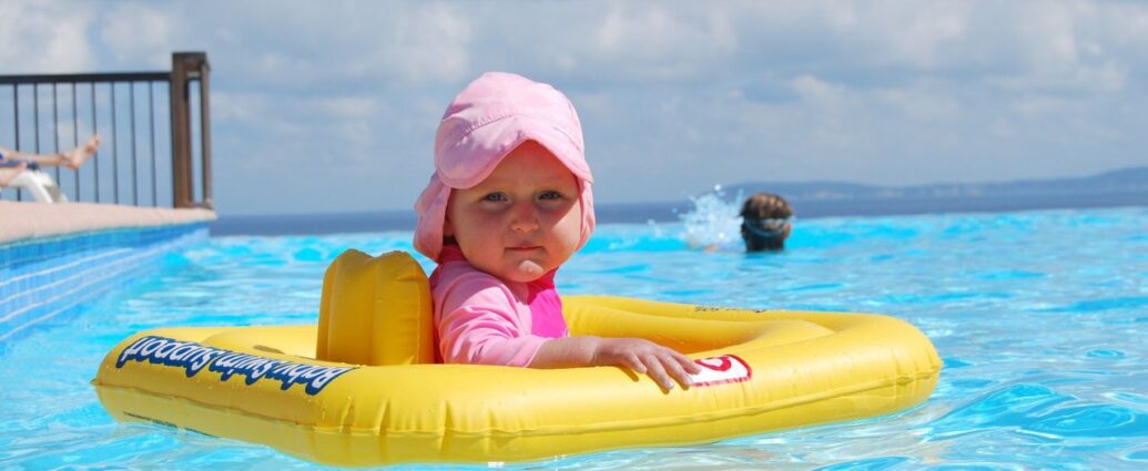 Dziewczynka pływa na żółtym pontonie w basenie