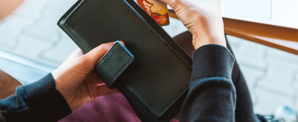 Kobieta trzyma w dłoniach czarny portfel