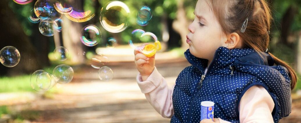 Dziewczynka bawi się bańkami mydlanymi w parku