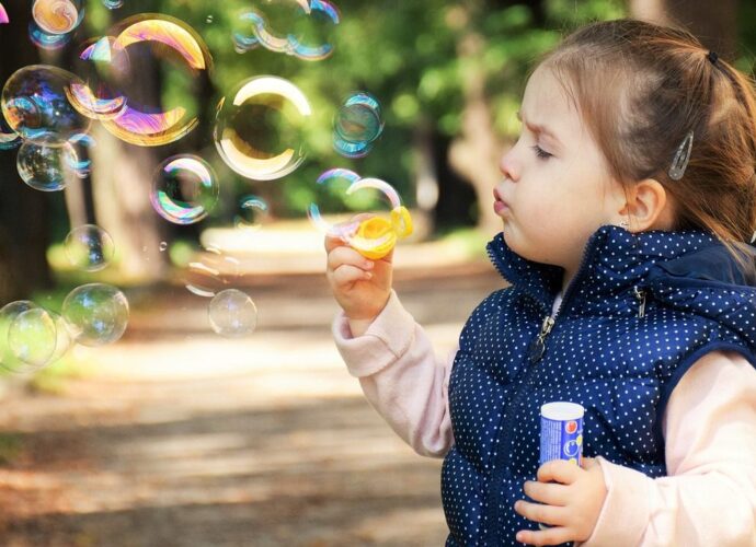 Dziewczynka bawi się bańkami mydlanymi w parku