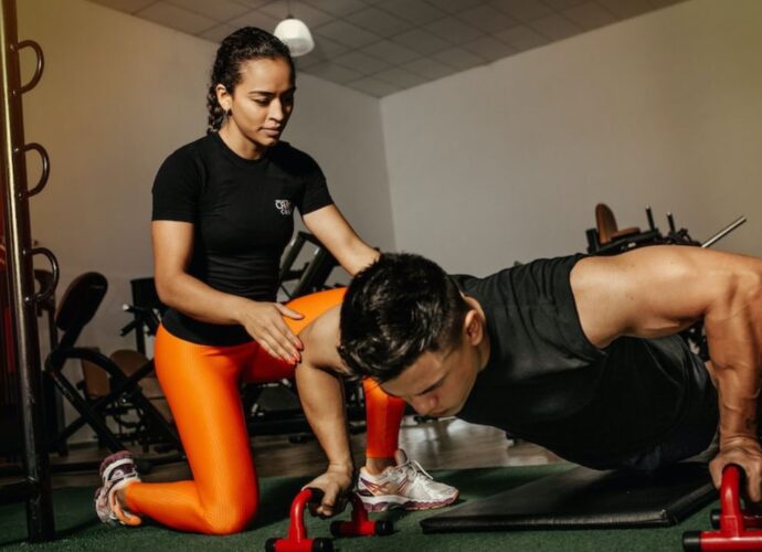 Mężczyzna trenuje na siłowni pod okiem trenerki