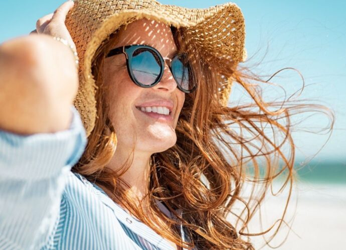 Kobieta w okularach przeciwsłonecznych i plażowym kapeluszu