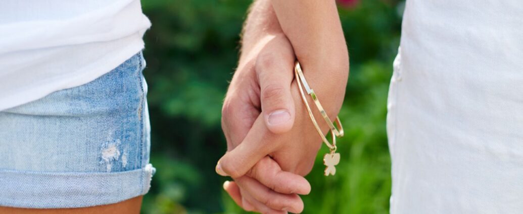 Para trzymająca się za ręce z bransoletką z charmsami