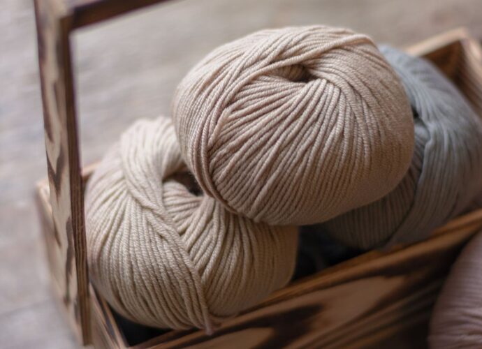 Motki beżowej włóczki w drewnianym pudełku