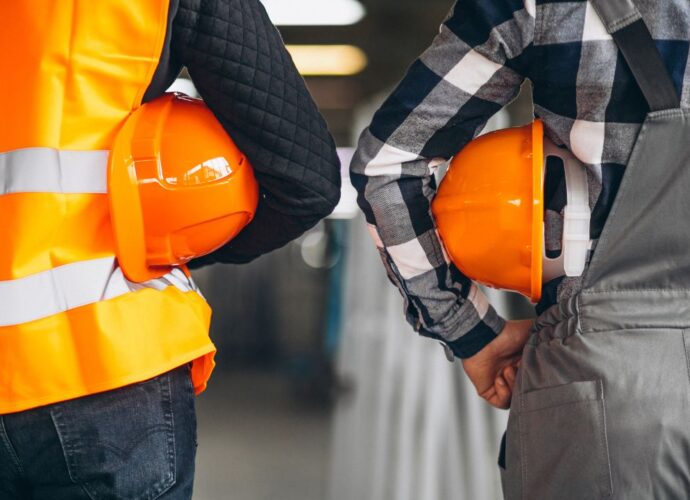 Pracownicy trzymają sprzęt BHP - pomarańczowe laski ochronne