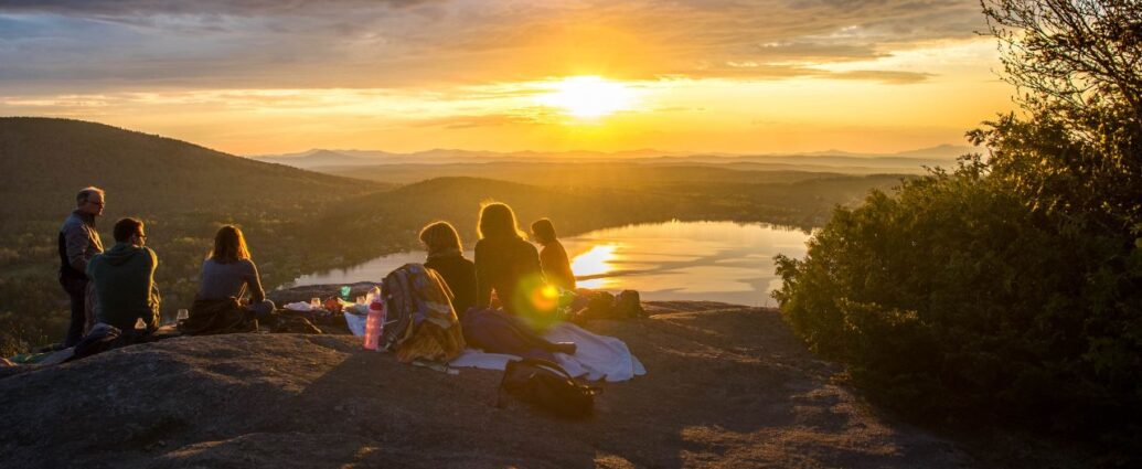 Grupa pracowników w czasie wyjazdu słuzbowego w góry podziwia zachód słońca