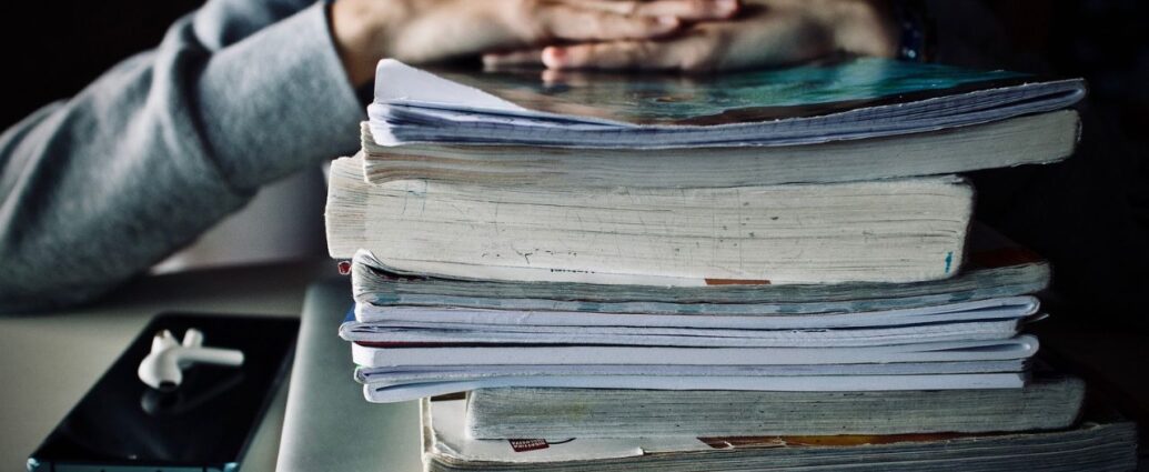 Uczeń siedzący nad stosem podręczników