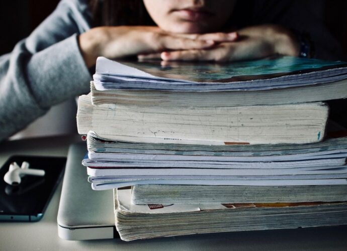 Uczeń siedzący nad stosem podręczników