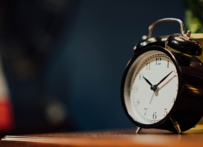 Zegar w formie budzika stojący na komodzie