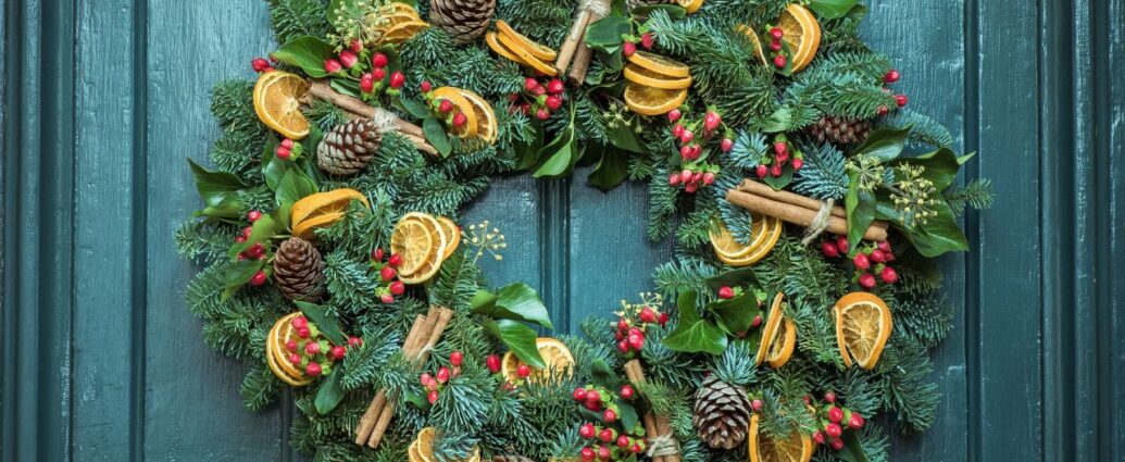 Świąteczny wieniec z suszonymi owocami powieszony na niebieskich drzwiach