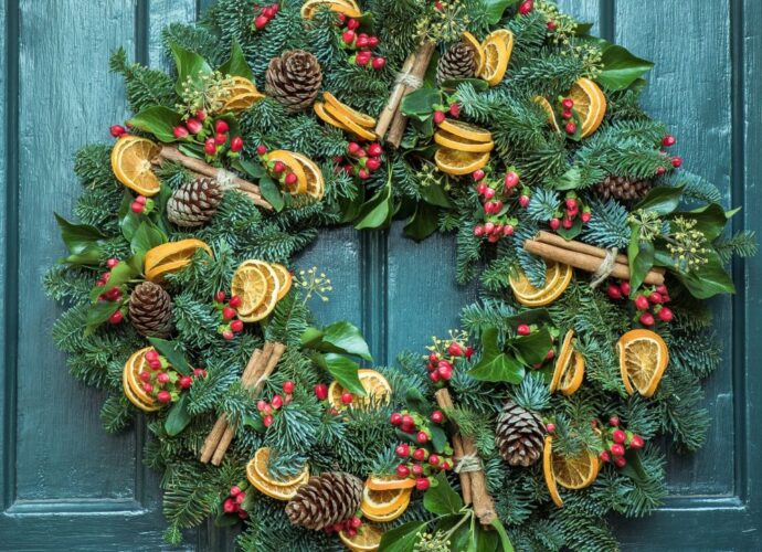 Świąteczny wieniec z suszonymi owocami powieszony na niebieskich drzwiach