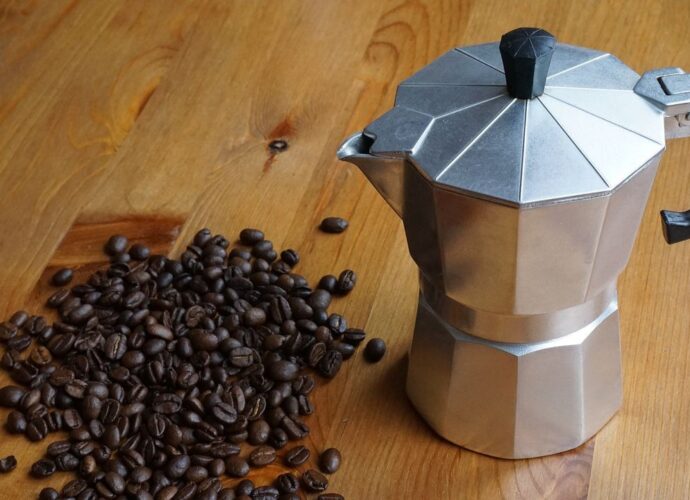 Tradycyjna kawiarka i rozsypane ziarna palonej kawy