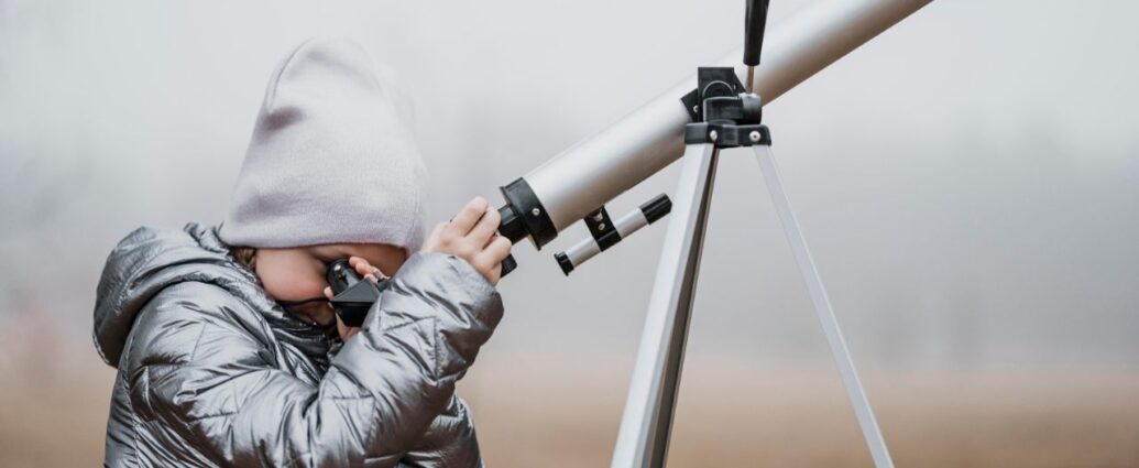 Chłopczyk obserwujący niebo przez teleskop astronomiczny