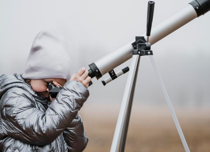 Chłopczyk obserwujący niebo przez teleskop astronomiczny