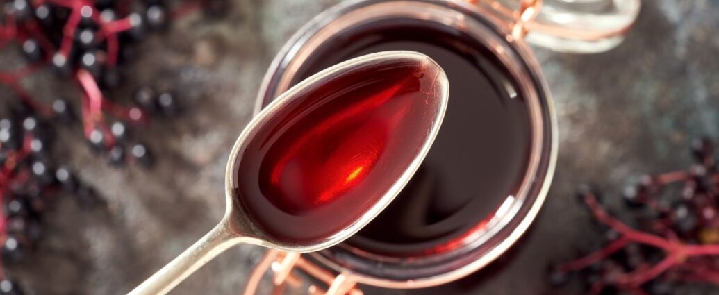 Łyżeczka syropu z czarnego bzu oraz słoik z syropem z tych owoców