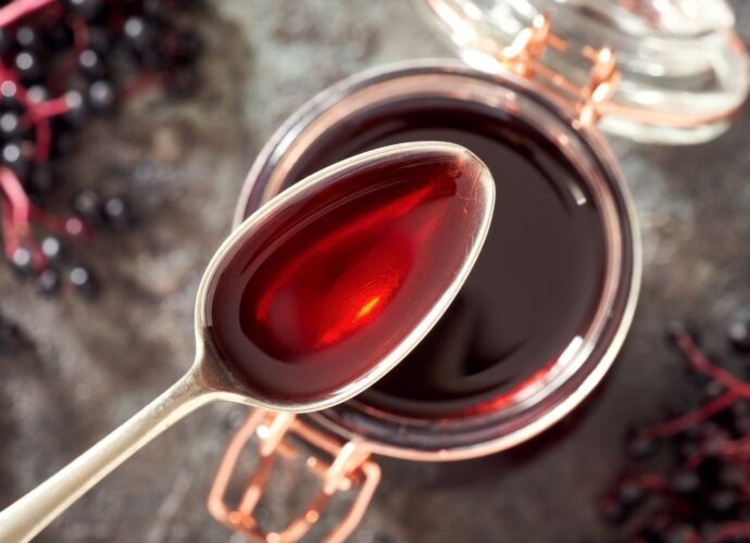 Łyżeczka syropu z czarnego bzu oraz słoik z syropem z tych owoców