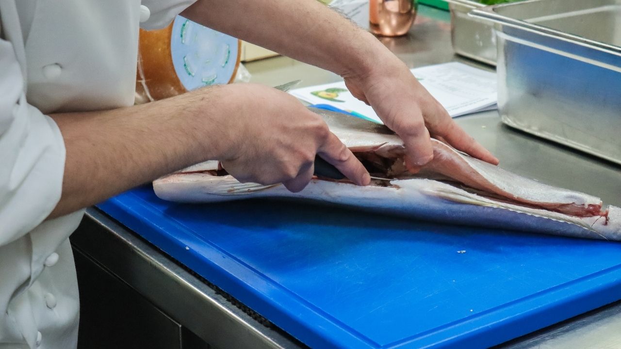 Kucharz filetuje rybę
