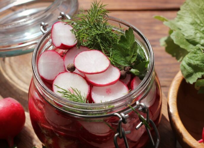 Jak kisić rzodkiewkę? Pokrojone rzodkiewki w słoiku przygotowane do kiszenia