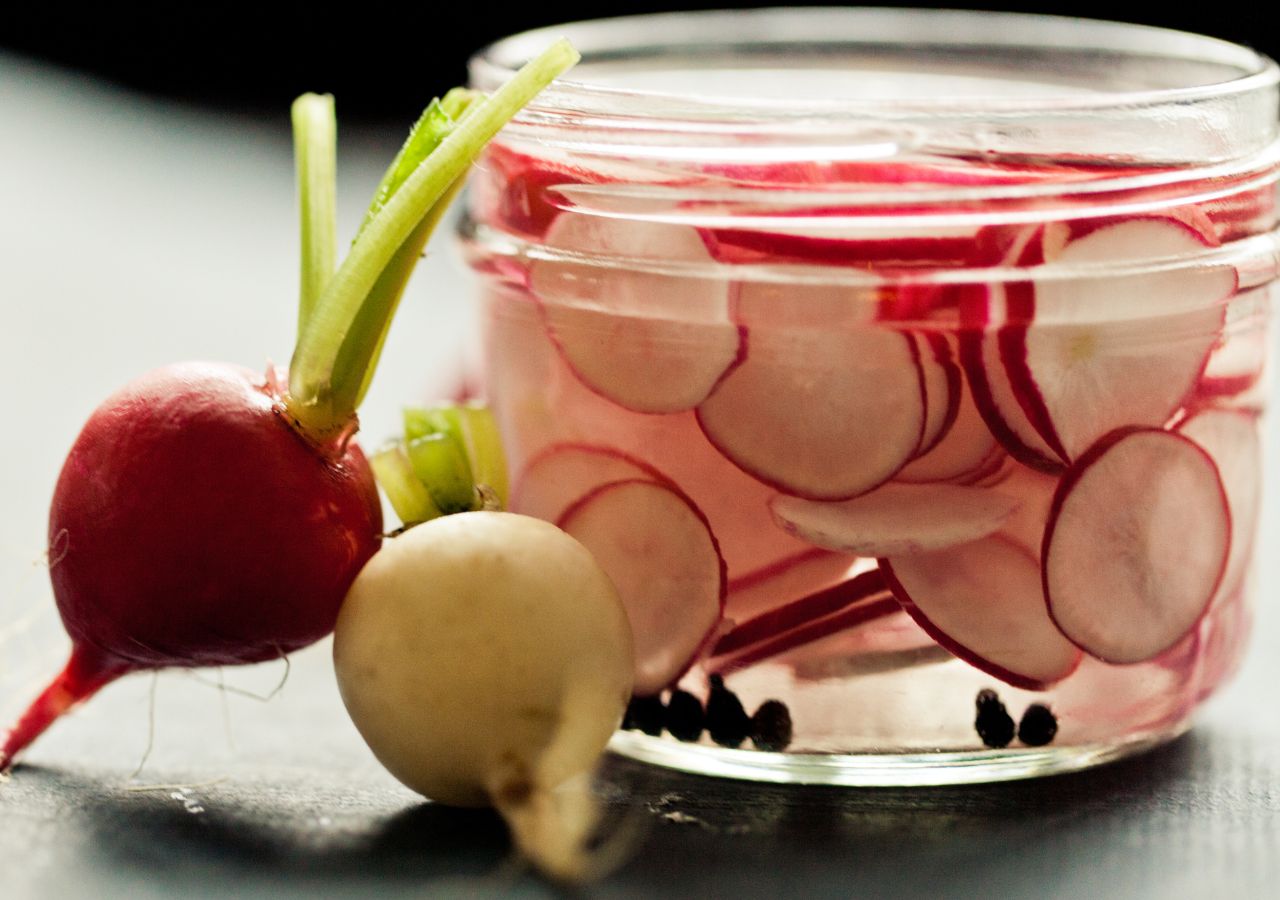 Słoik z pokrojonymi rzodkiewkami, zalanymi solanką, gotowymi do kiszenia