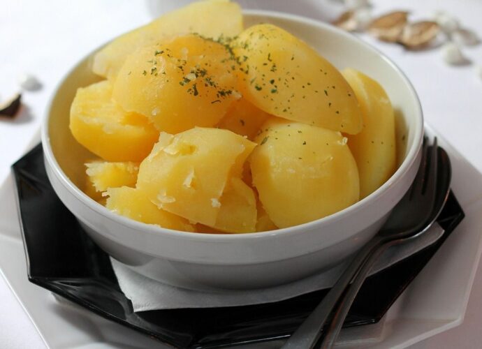 Gotowane ziemniaki w białej misce, posypane ziołami