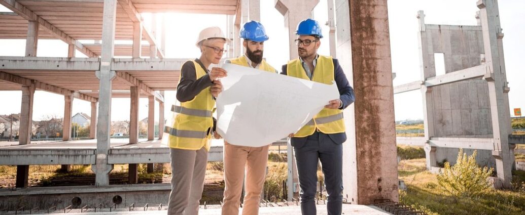Pracownicy na terenie budowy przeglądają dokumentację
