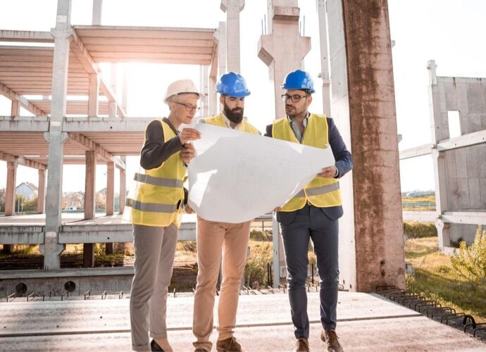 Pracownicy na terenie budowy przeglądają dokumentację