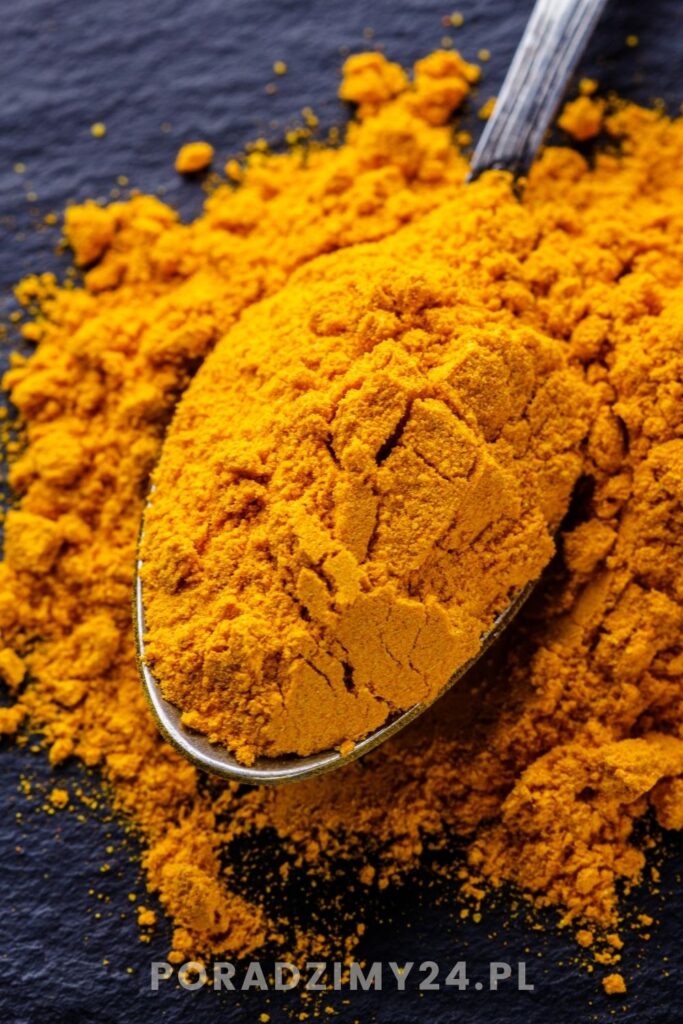 Suszona kurkuma na łyżce oraz przyprawa rozsypana na blacie