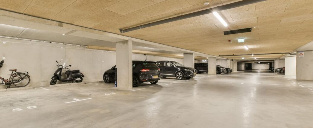 Garaż podziemny z zaparkowanym samochodami, motocyklem i rowerem