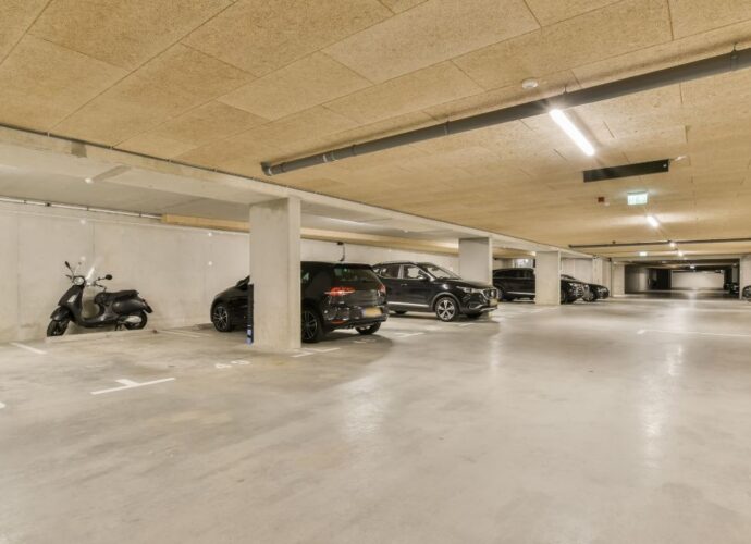 Garaż podziemny z zaparkowanym samochodami, motocyklem i rowerem