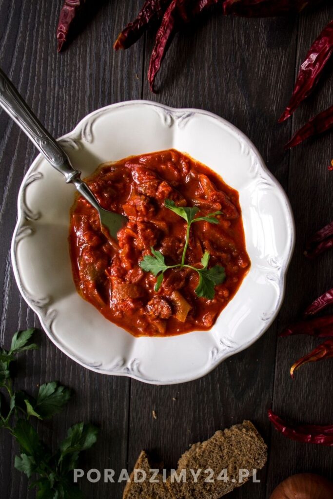 Talerz z leczo. Obok strąki suszonej ostrej papryki